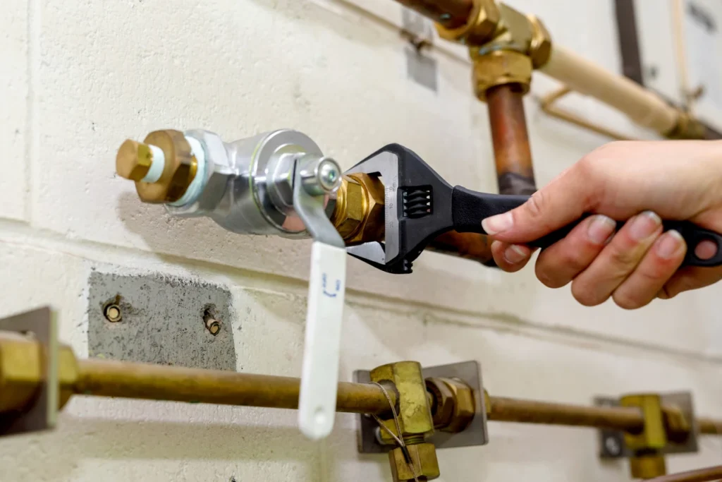 A plumber adjusting a pipe with a wrench